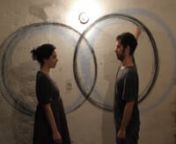 A man and a woman stand in front of each other and next to a white wall. In their ritual, they both start to move their arms in a circular way, holding a dark charcoal to trace their gesture. Straight bodies in curvilinear progression. Still, but in motion. Centripetal movement that centers the self. The action, that touches the wall as in a tangential, is at the same time it&#39;s present and past, cause and effect. It is followed by it&#39;s own register and track. As time passes, the line becomes thi